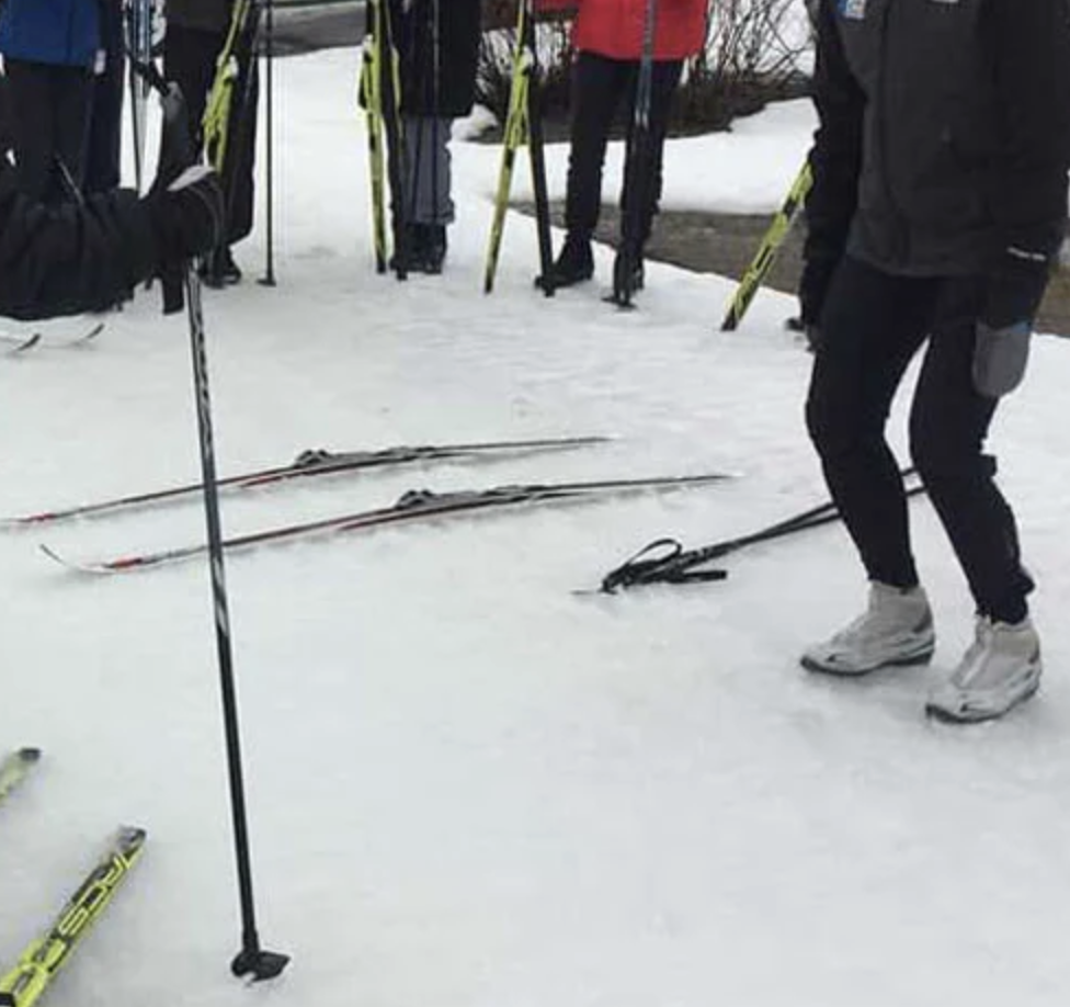 person w bent knees surrounded by people learning to ski